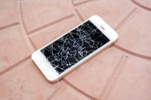 broken smartphone screen. Smartphone with a broken screen on the tile floor. Side view broken phone. negligence