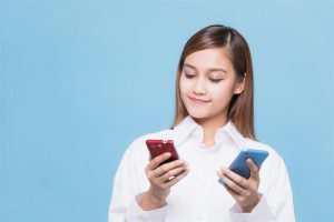 Woman with brown hair comparing tow mobile devices in her hands