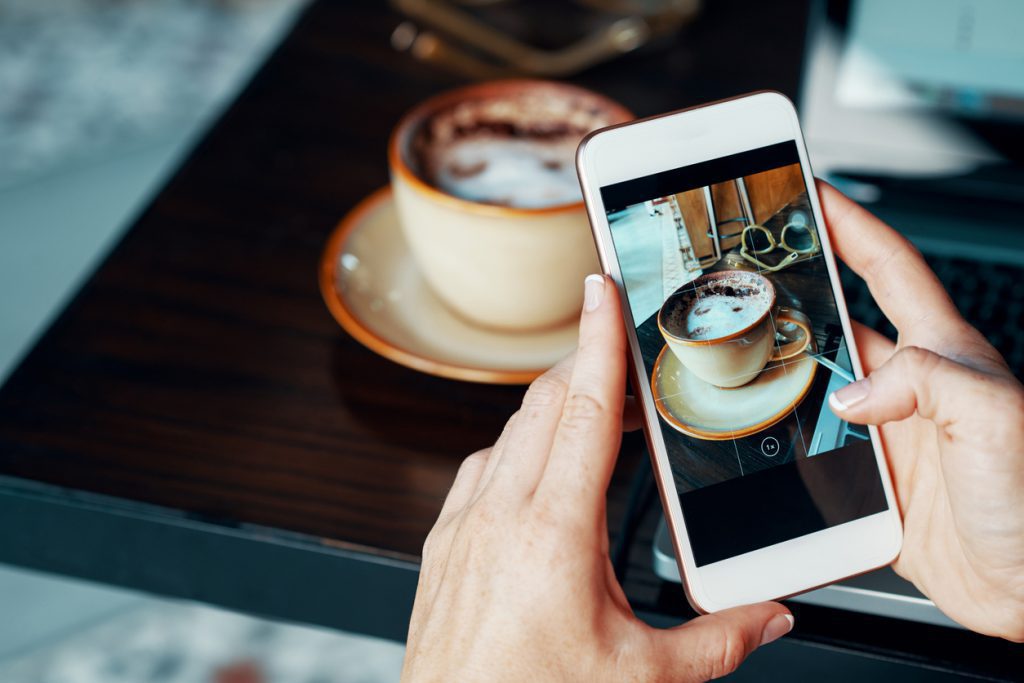 Female blogger taking photo of her coffee to make a post