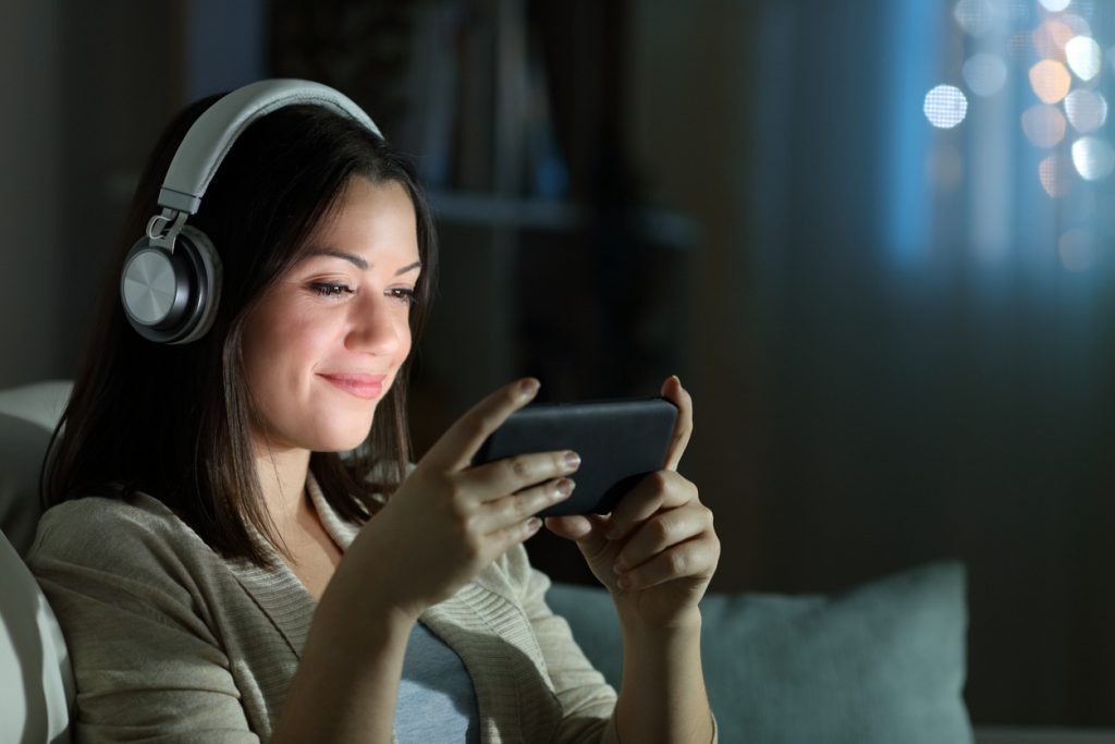woman watching video at night comfortably at home
