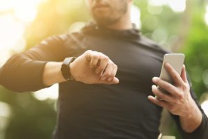 Man checking fitness watch and holding whole while on a run