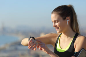 Runner wearing earbuds checks music on smartwatch