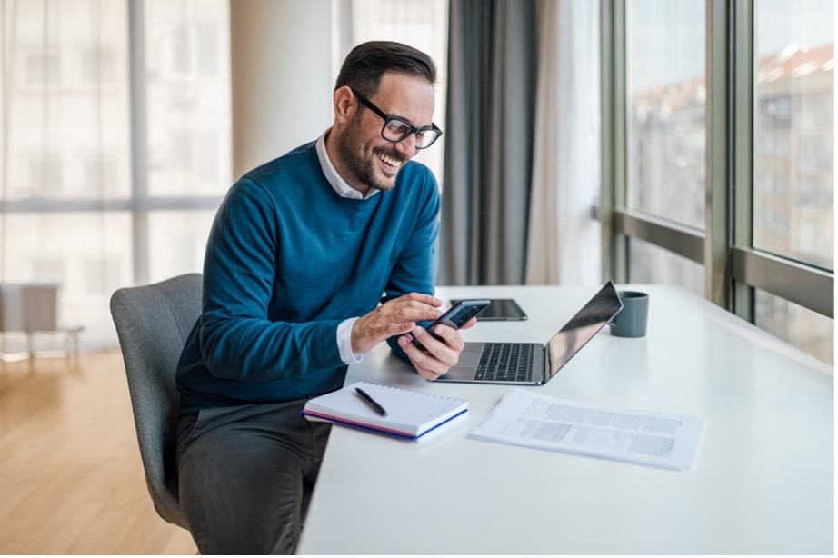 A person sitting at a desk looking at his phone
