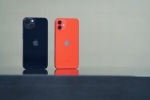 Two iphones stood up next to each other, one coral one black 